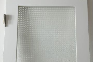 ドアを窓付ドアにリメイク!既存の小さな丸窓は穴埋めし、上部にチェッカーガラスをはめ込み明り取りを制作。