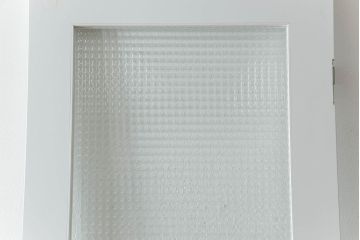 ドアを窓付ドアにリメイク!既存の小さな丸窓は穴埋めし、上部にチェッカーガラスをはめ込み明り取りを制作。