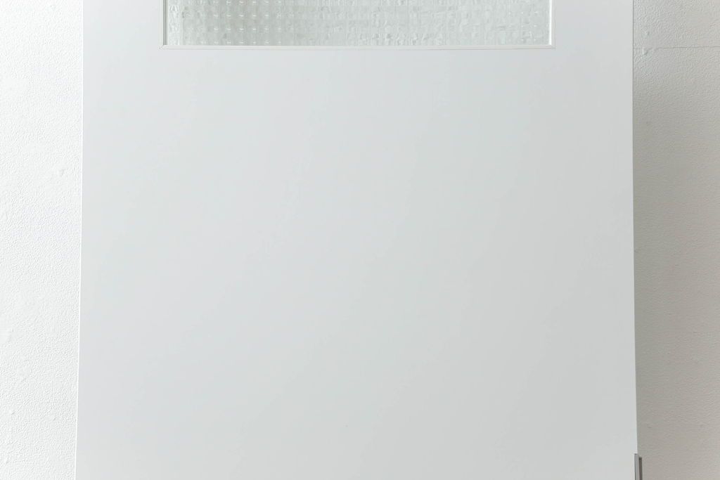 ドアを窓付ドアにリメイク!既存の小さな丸窓は穴埋めし、上部にチェッカーガラスをはめ込み明り取りを制作。