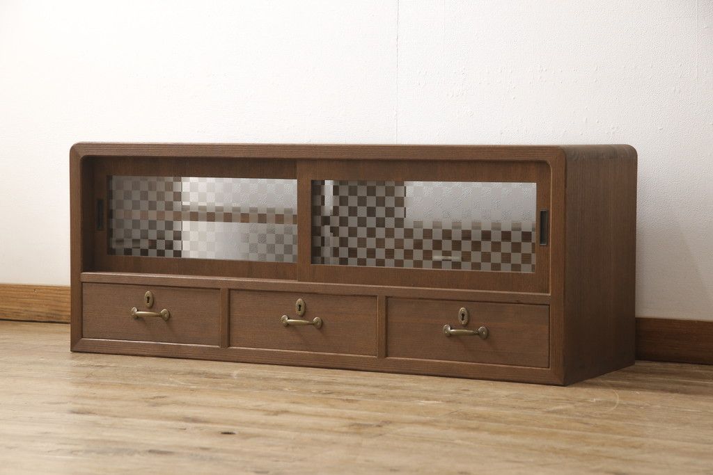 桐箪笥の上段を用いてローボードにリメイク!高さと奥行きをリサイズ。棚を製作し、背面はオープンに。引き戸は市松模様のガラスをはめ込み、取っ手と鍵金具を交換。チェスナット系に着色仕上げ。