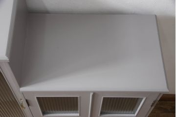 書棚を使いやすくリメイク!上部のオープン部分をカットし、天板を設置。ガラスが欠損した部分にモールガラスをはめ込み、背板を新材に交換。両開き戸内の底面を補強して、台輪をカットし脚を取り付け。取っ手・引手を交換して、ご希望の色に着色仕上げ。