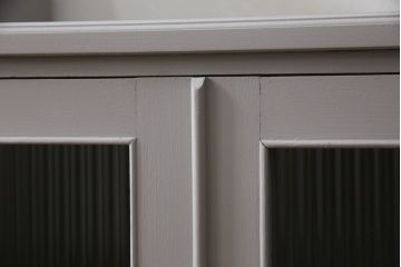 書棚を使いやすくリメイク!上部のオープン部分をカットし、天板を設置。ガラスが欠損した部分にモールガラスをはめ込み、背板を新材に交換。両開き戸内の底面を補強して、台輪をカットし脚を取り付け。取っ手・引手を交換して、ご希望の色に着色仕上げ。